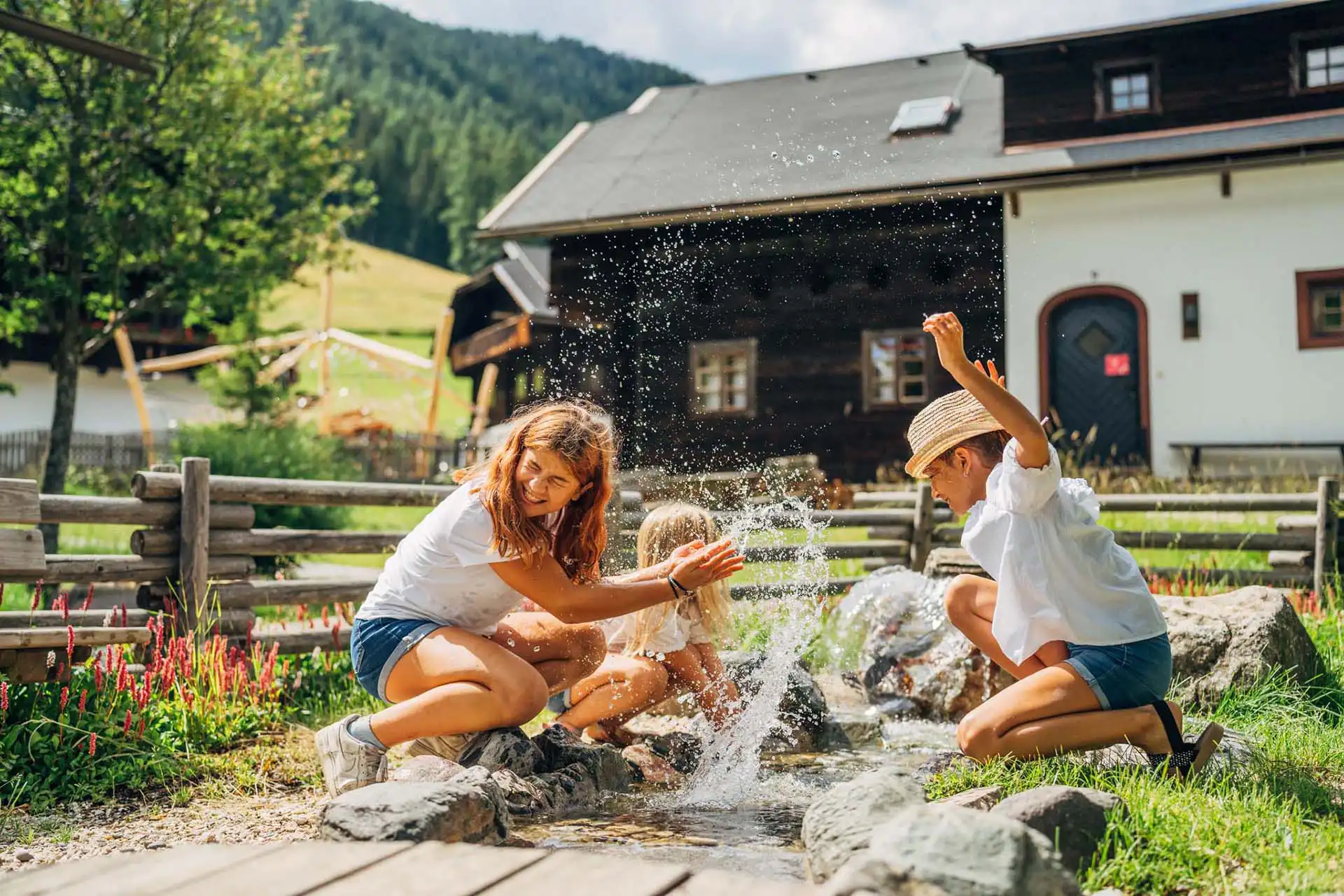 Zwei Mädchen spielen beim Kärnten Sommerurlaub am Wasserspielplatz im Slow Travel Resort Kirchleitn.