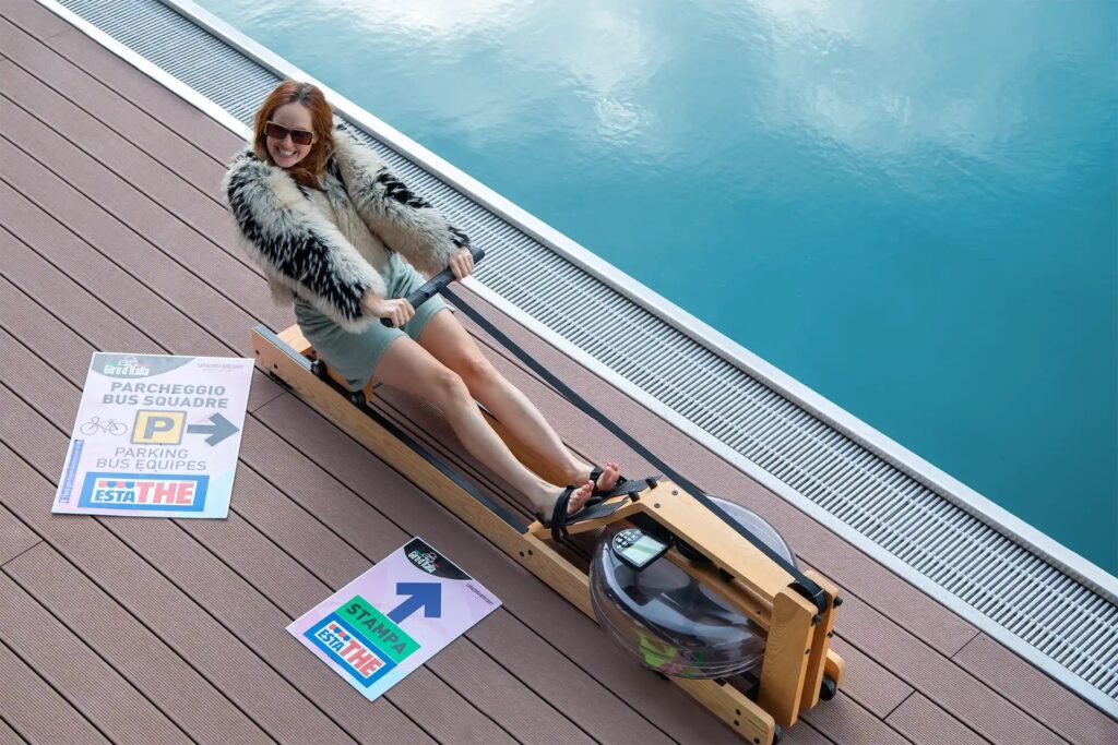 Slowfluencer Giulia Bewerbung als Slowfluencer: Frau macht in stylischem Party-Outfit Sport auf Rudergerät am Pool